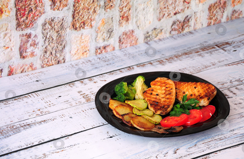 Скачать Вкусный обед: два куриных стейка, жареный картофель, листья салата, помидоры, брокколи и грибы. фотосток Ozero