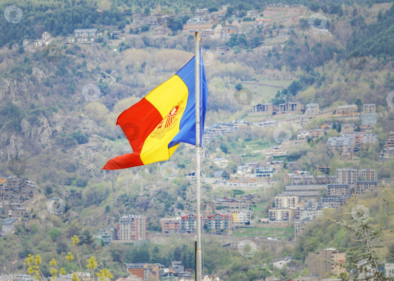 Скачать Флаг Андорры на фоне гор и домов. фотосток Ozero