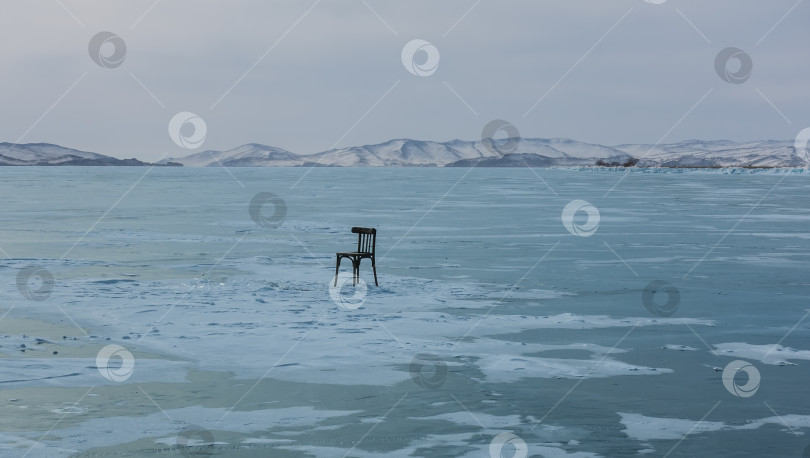 Скачать Одинокий деревянный стул стоит на ледяном и заснеженном озере.  Озеро Байкал. Россия фотосток Ozero