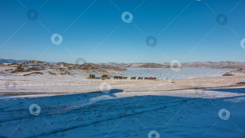 Скачать Небольшая деревушка на берегу озера.  Озеро Байкал покрыто льдом. фотосток Ozero