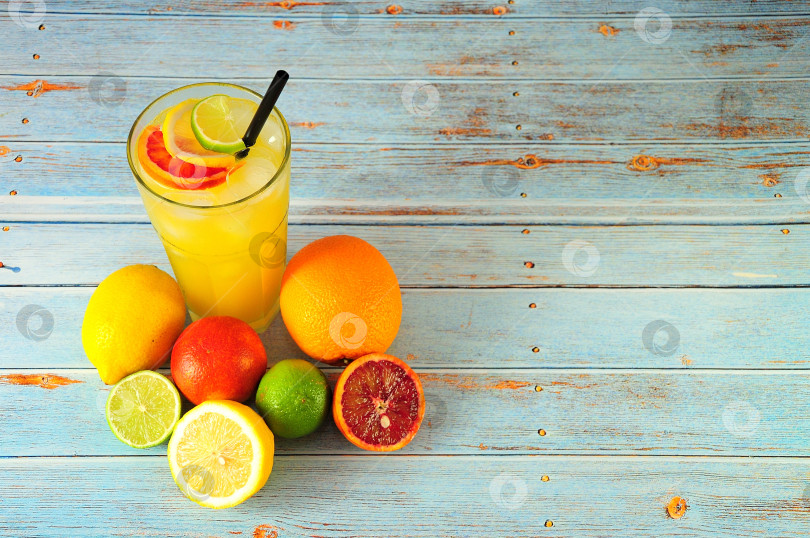 Скачать Смешайте цитрусовые в высоком бокале со льдом, поставьте рядом с лаймом, лимоном, апельсином и грейпфрутом на деревянный стол. фотосток Ozero