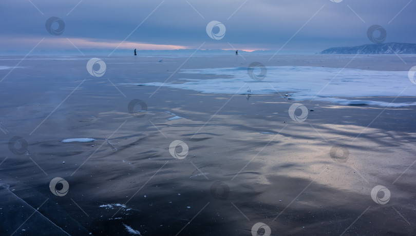 Скачать На гладкой поверхности замерзшего озера видны фрагменты льда и участки снега. фотосток Ozero