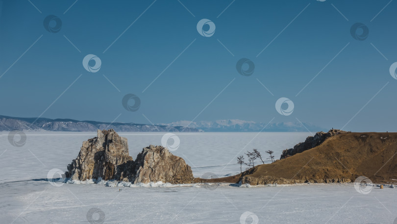 Скачать Замерзшее озеро покрыто льдом и снегом. Над его поверхностью возвышается живописная двуглавая скала.= фотосток Ozero