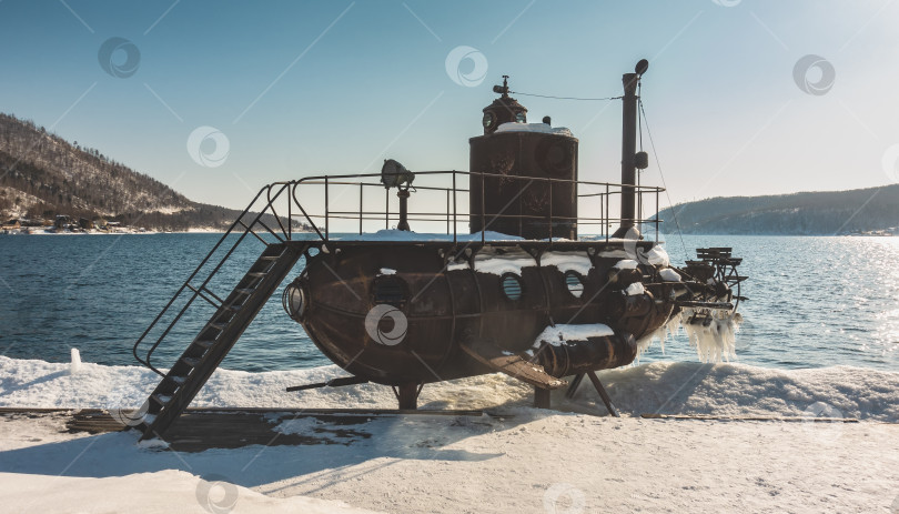 Скачать Старая подводная лодка стоит на заснеженном берегу реки. фотосток Ozero