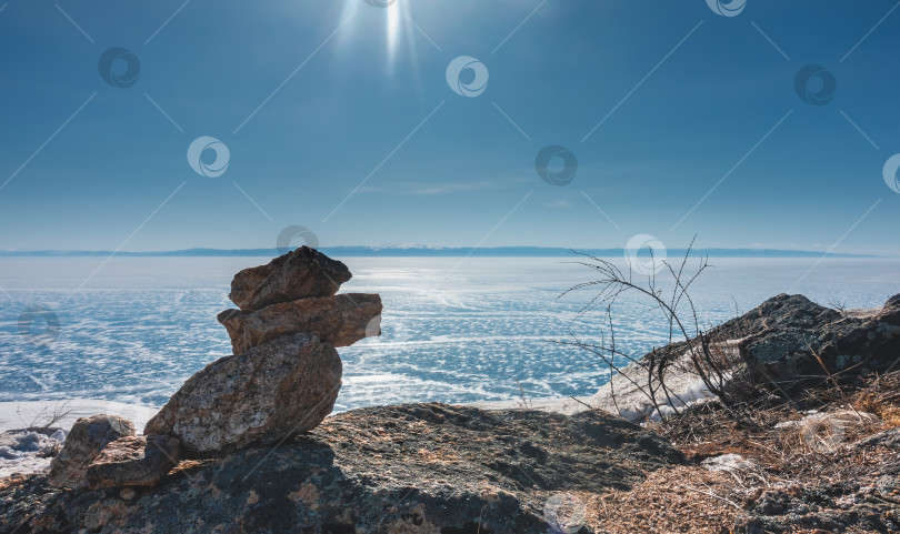 Скачать Голубой лед озера покрыт снегом, похожим на кружево. На переднем плане - пирамида, сложенная из камней. фотосток Ozero