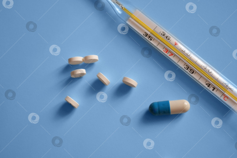 Скачать термометр, капсулы и таблетки на синем фоне, фото для фотосток Ozero