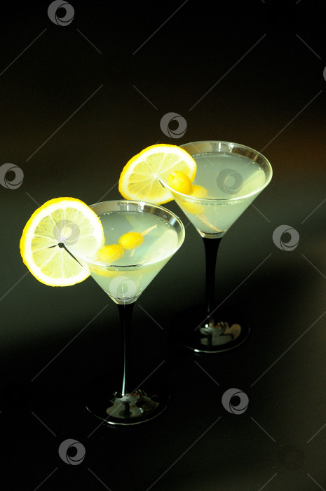 Скачать Два бокала белого вермута с оливками и ломтиками лимона на черном фоне. фотосток Ozero