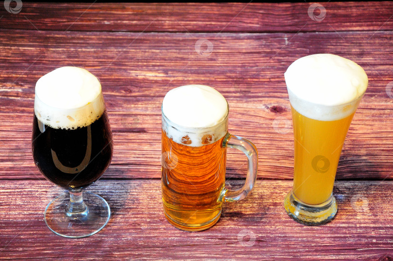 Скачать Три разных бокала пива, пшеничного, светлого и темного, на деревянном столе. фотосток Ozero
