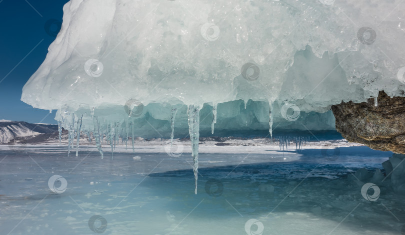 Скачать Подножие скалы на замерзшем озере покрыто толстым слоем ледяных брызг. фотосток Ozero