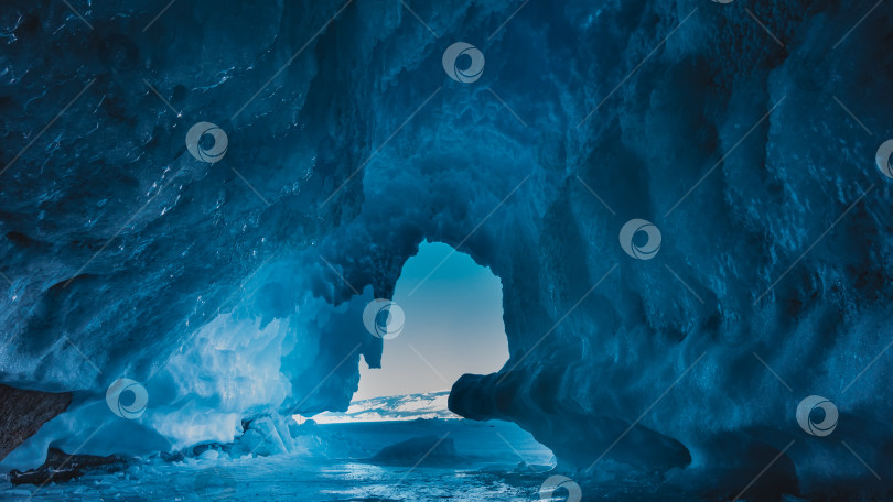 Скачать Необычный грот в скале полностью покрыт блестящим голубым льдом, сосульками. фотосток Ozero