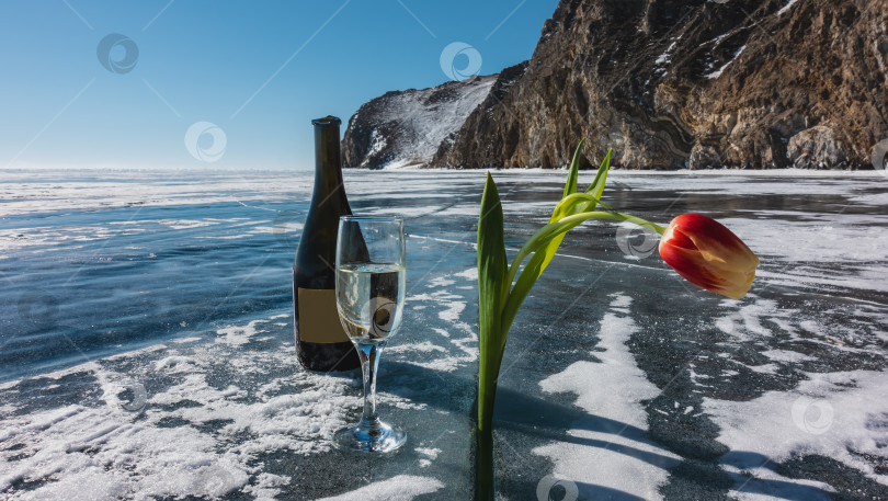 Скачать На поверхности замерзшего озера лежит открытая бутылка и бокал шампанского. фотосток Ozero