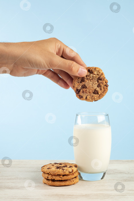 Скачать Мужская рука, держащая стакан молока и печенье на синем фоне фотосток Ozero