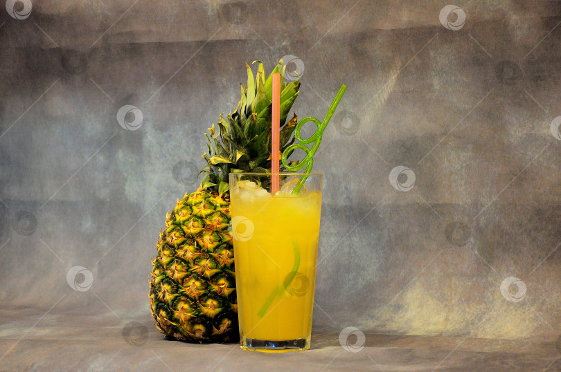 Скачать Стакан ананасового сока со льдом на сером фоне. фотосток Ozero