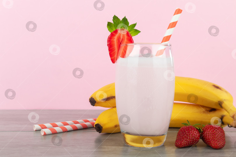 Скачать Банановый молочный коктейль со свежей клубникой на розовом фоне. фотосток Ozero
