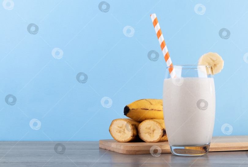 Скачать Банановый смузи в стакане с соломинкой на синем фоне фотосток Ozero