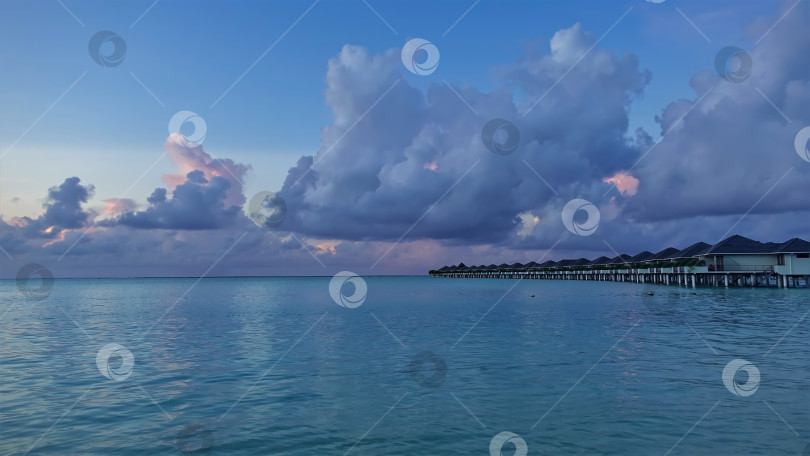 Скачать Аквамариновый океан спокоен. Над водой - ряд вилл. фотосток Ozero