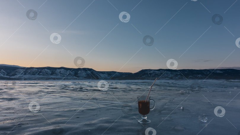 Скачать На замерзшем озере стоит стеклянная кружка с глинтвейном.  Осколки льда валяются неподалеку. Байкал фотосток Ozero