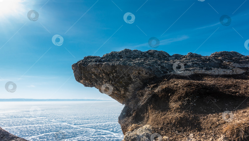Скачать Плоская скала нависает над замерзшим озером на фоне голубого неба. Текстура камня. фотосток Ozero