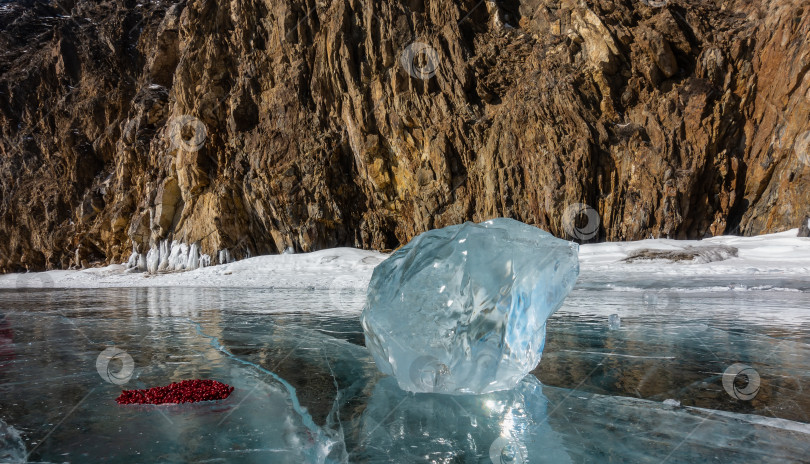 Скачать Блестящий осколок льда лежит на замерзшем озере. Рядом лежит брусника, выложенная в форме сердечка. фотосток Ozero