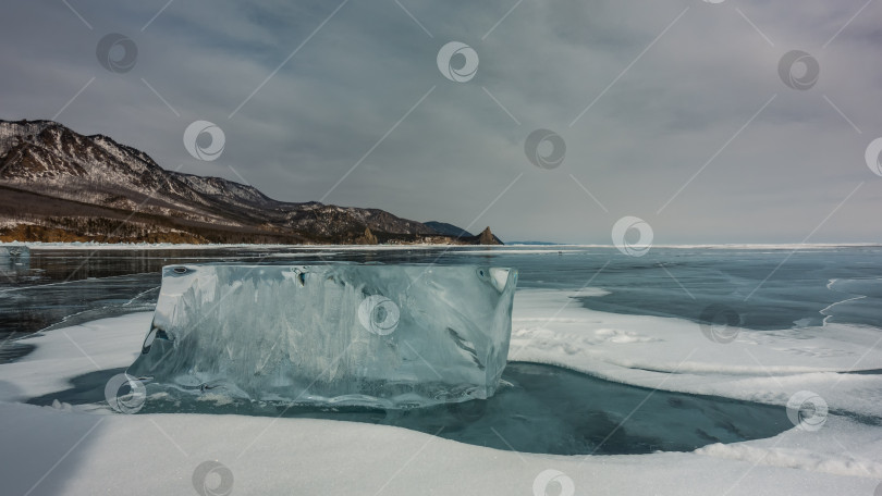 Скачать На замерзшем озере лежит большая прозрачная льдина, окруженная снегом. фотосток Ozero
