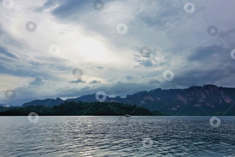 Скачать По поверхности озера пробегает рябь. По воде плывет лодка. фотосток Ozero