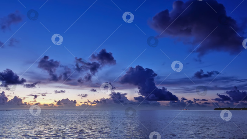 Скачать Солнце скрылось за горизонтом. На вечернем небе оранжевая иллюминация и фиолетовые кучевые облака. фотосток Ozero