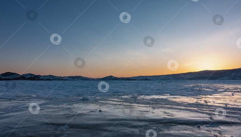Скачать Закат над замерзшей озерной равниной. Солнце скрылось за горным хребтом. фотосток Ozero