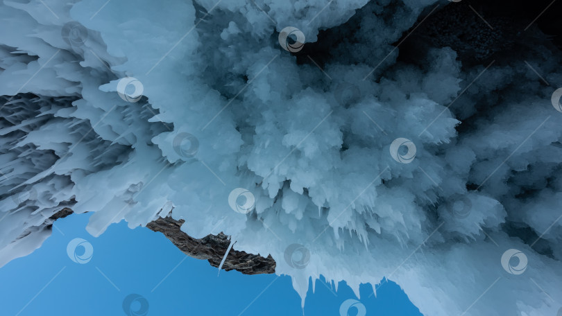 Скачать Сосульки-сталактиты свисают с потолка каменного грота в скале. фотосток Ozero