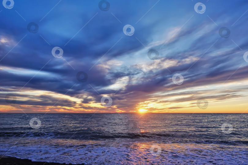 Скачать Красочный закат над морем. На небе голубые и розовые облака, горизонт выделен оранжевым цветом. фотосток Ozero