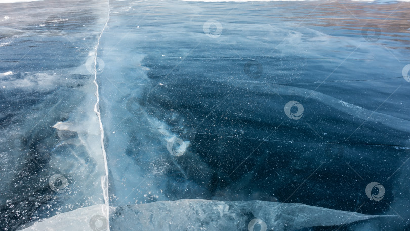 Скачать Гладкую голубую поверхность льда пересекают глубокие трещины. фотосток Ozero