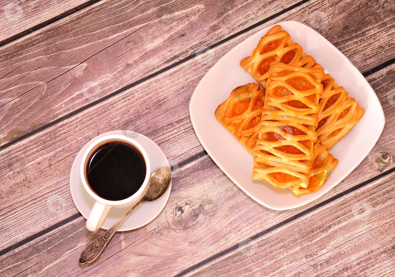 Скачать Несколько свежих слоеных пирожных с фруктовым джемом и чашка свежего черного кофе на деревянном столе. фотосток Ozero