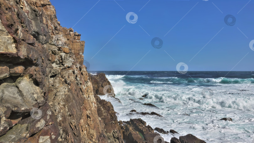 Скачать Бирюзовые волны Атлантического океана разбиваются об отвесные скалы мыса Доброй Надежды. фотосток Ozero