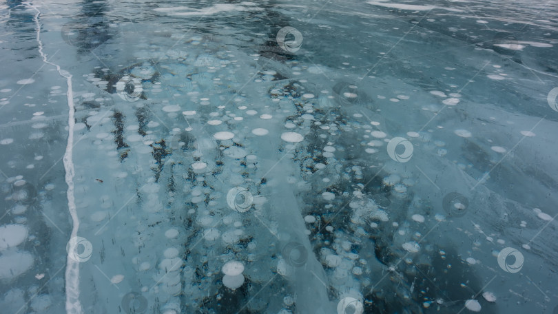 Скачать Ледяная поверхность. Крупный план.  Трещины и столбы замерзших пузырьков метанового газа фотосток Ozero