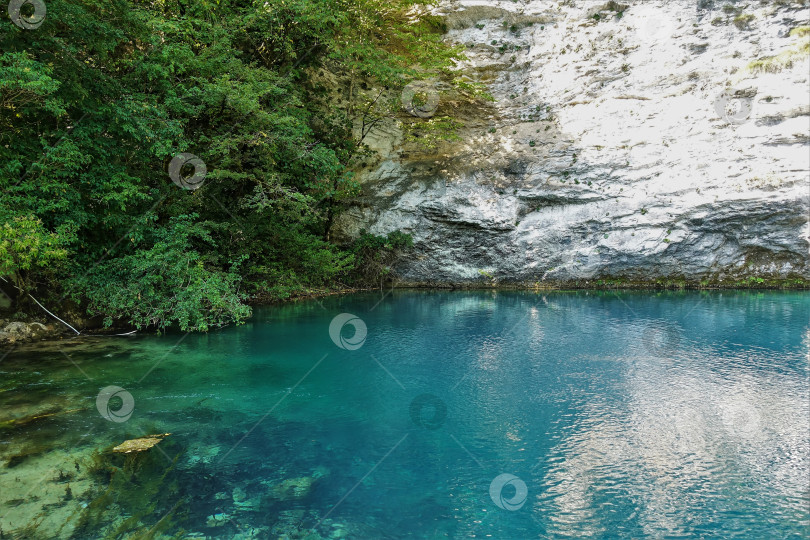 Скачать Озеро окружено отвесными скалами. Аквамариновая вода спокойна и прозрачна. фотосток Ozero