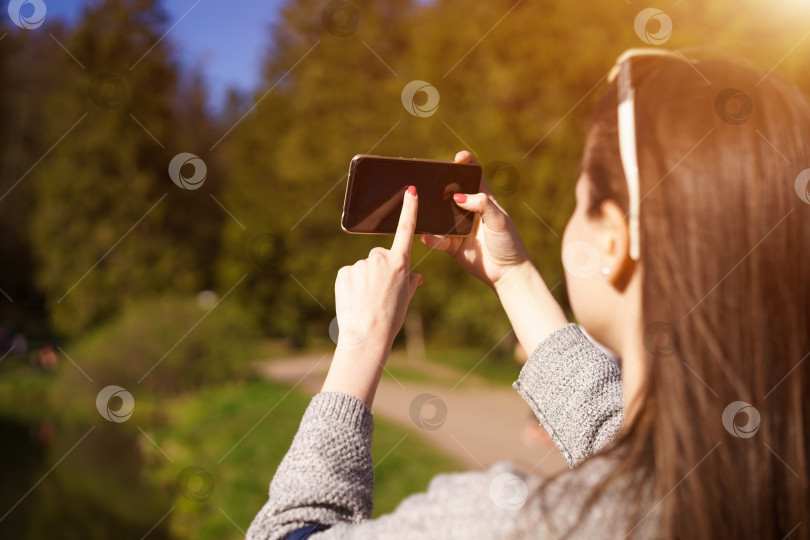 Скачать девушка брюнетка в солнцезащитных очках держит в руках телефон и фотографирует себя фотосток Ozero