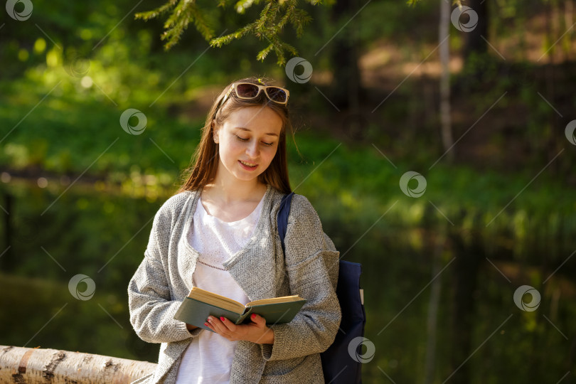 Скачать Симпатичная девушка в парке с книгой в руке фотосток Ozero