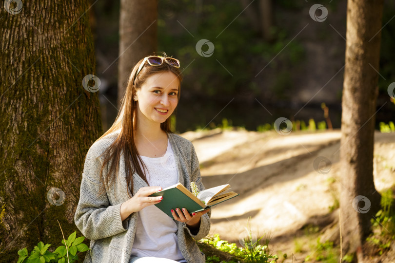 Скачать Симпатичная девушка в парке с книгой в руке фотосток Ozero