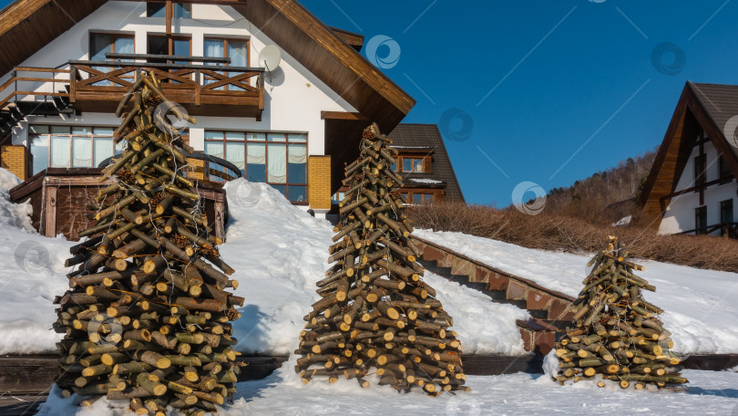 Скачать Три рождественские елки сделаны из веток и бревен, украшены сосновыми шишками, фонариками. фотосток Ozero