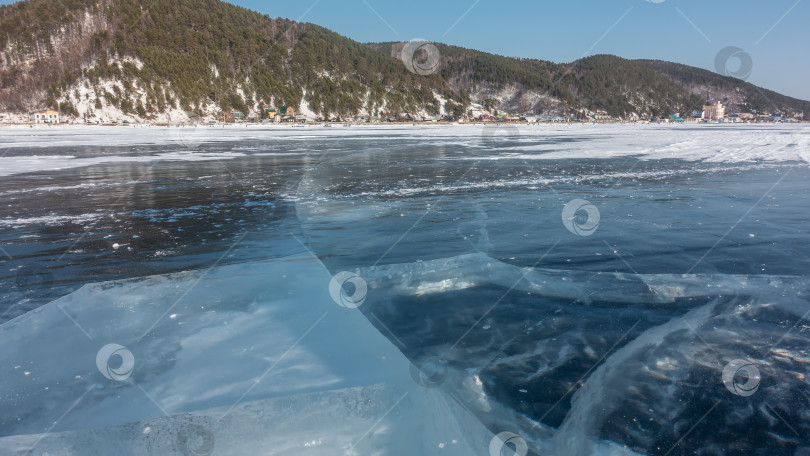 Скачать На гладком льду замерзшего озера видны глубокие трещины и участки снега.  Байкал фотосток Ozero