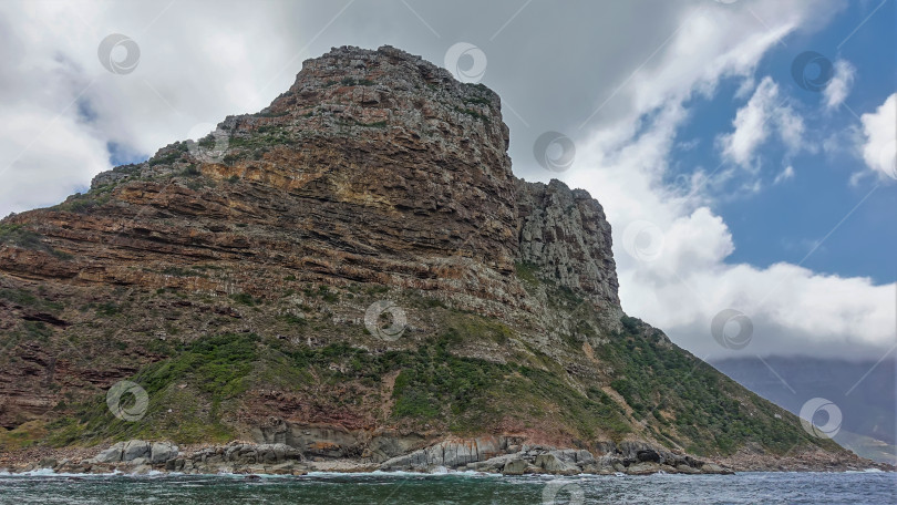 Скачать Живописная скала с редкой растительностью возвышается на берегу Атлантического океана. фотосток Ozero