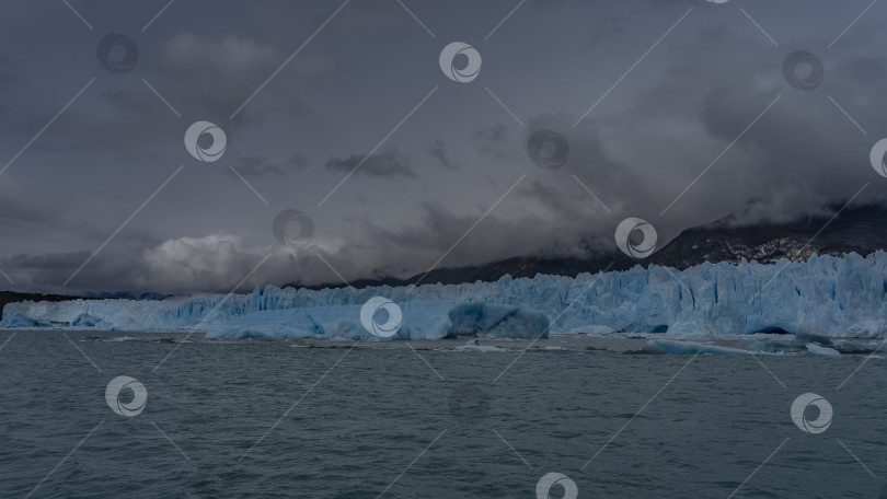 Скачать Над озером возвышается стена голубого льда. Разбитые глыбы айсбергов плавают в бирюзовой воде. фотосток Ozero