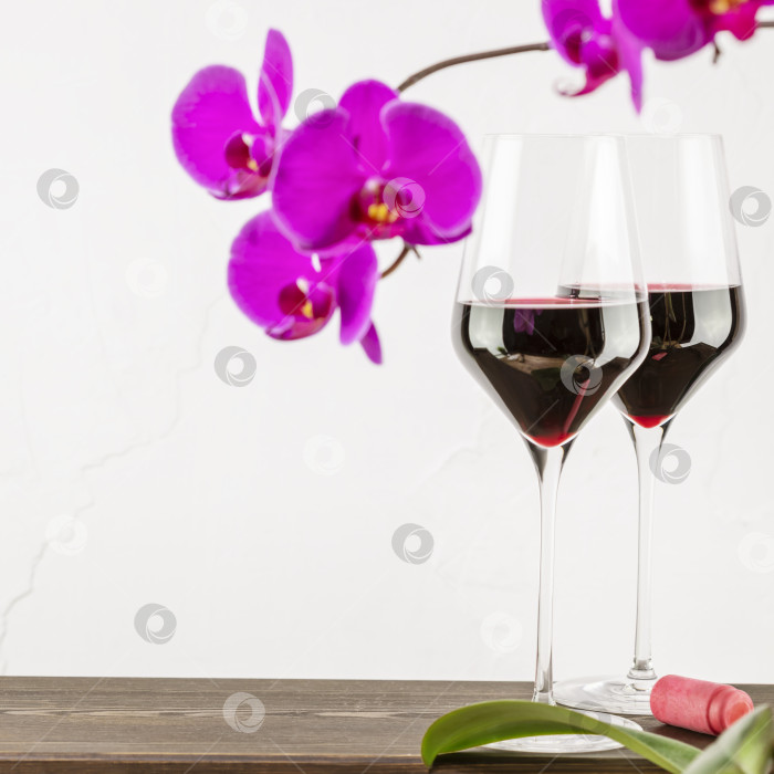Скачать Бокалы для вина с натуральным красным вином. на деревянном столе с орхидеями фотосток Ozero