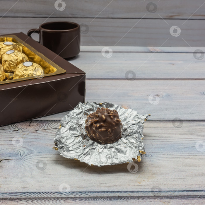 Скачать Шоколадная конфета с орехами лежит на дощатой поверхности. фотосток Ozero