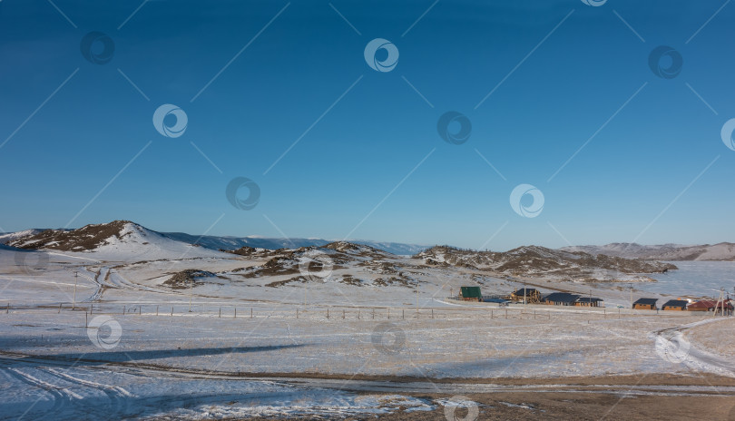 Скачать Зимний сибирский пейзаж. На берегу замерзшего озера стоят деревянные домики туристической базы. фотосток Ozero