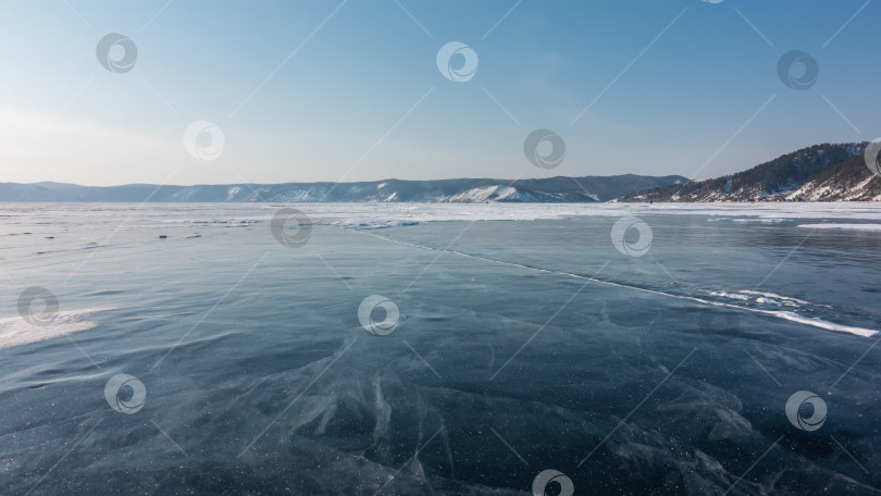 Скачать На гладком льду замерзшего озера видны трещины и немного снега. фотосток Ozero