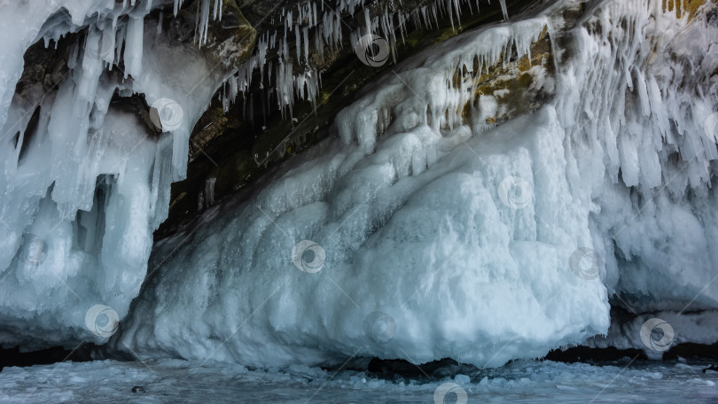 Скачать Основание гранитной скалы покрыто толстым слоем льда, причудливыми сосульками. фотосток Ozero