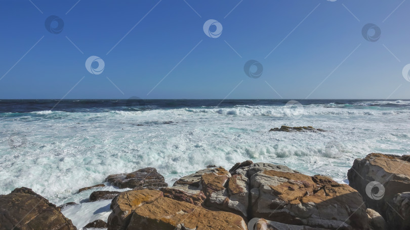 Скачать Мыс Доброй Надежды в Кейптауне. Волны бирюзового Атлантического океана разбиваются о прибрежные валуны фотосток Ozero