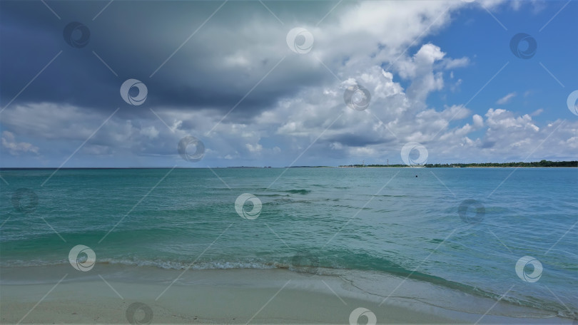 Скачать Темное облако нависло над аквамариновым океаном среди белых облаков. фотосток Ozero
