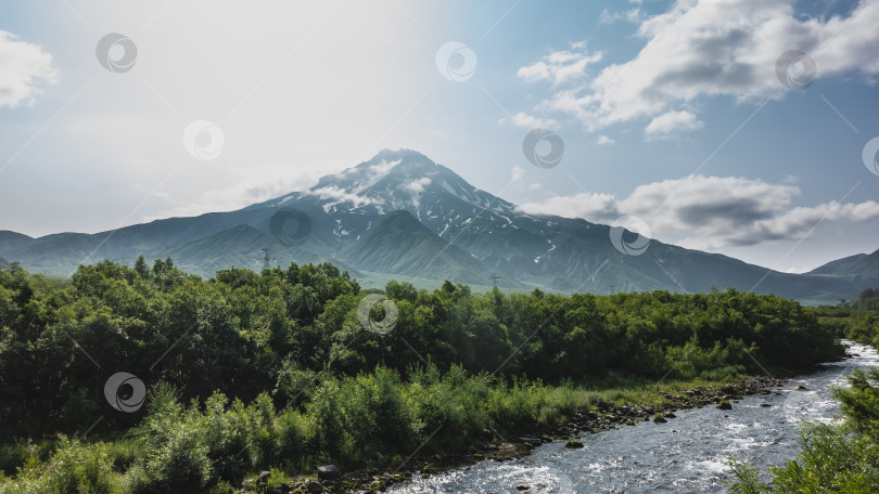 Скачать Вулкан с заснеженной вершиной на фоне голубого неба с облаками. фотосток Ozero