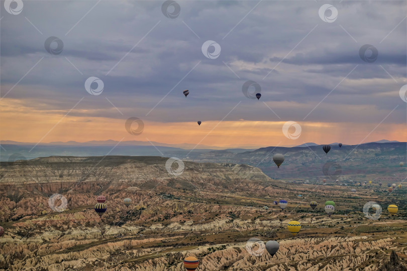 Скачать Разноцветные воздушные шары над Каппадокией. Облачное небо с оранжевой подсветкой. фотосток Ozero